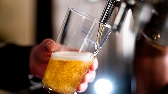 Bartender pouring crafted beer from tap in glass